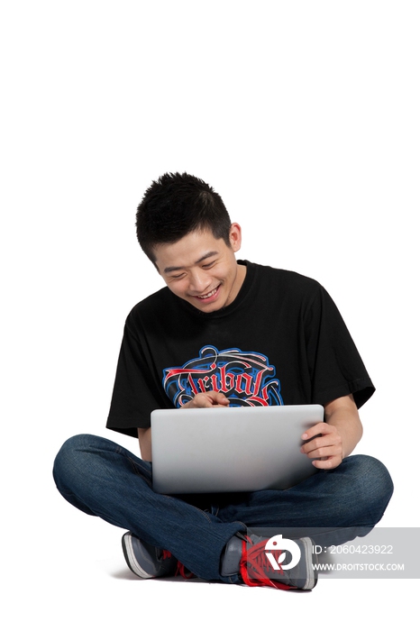 棚拍年轻男人盘腿坐在地上玩电脑
