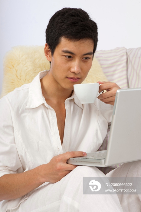 年轻男人边喝咖啡边看笔记本电脑