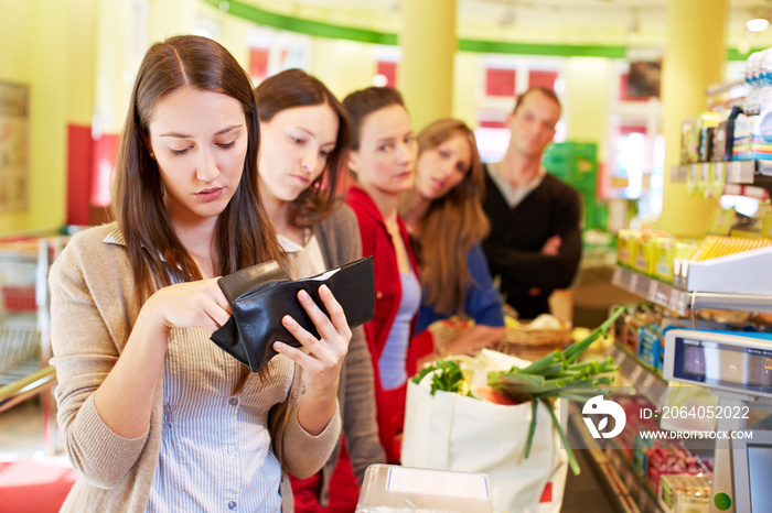 Frau sucht Geld an Supermarktkasse