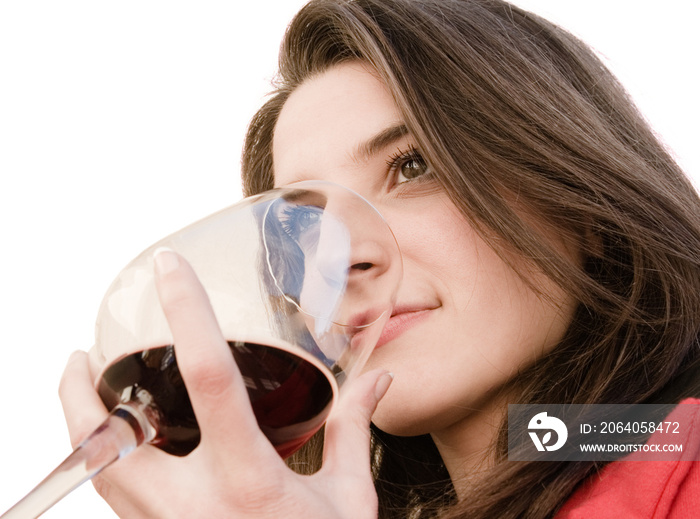 一个美丽的女人闻着一杯红色的葡萄酒