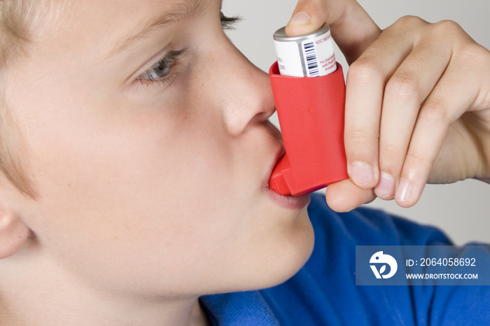 Asthma inhaler being used by boy in blue shirt