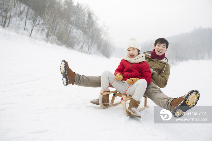 父女俩乘雪橇滑雪