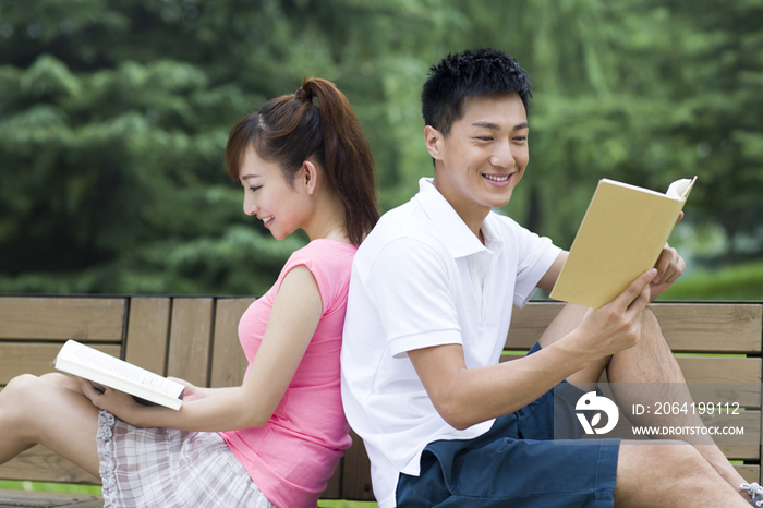 年轻情侣在公园看书