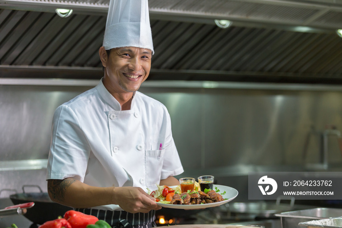 Portrait of a smiling male chef with cooked food standing in the kitchen, Chef Thailand