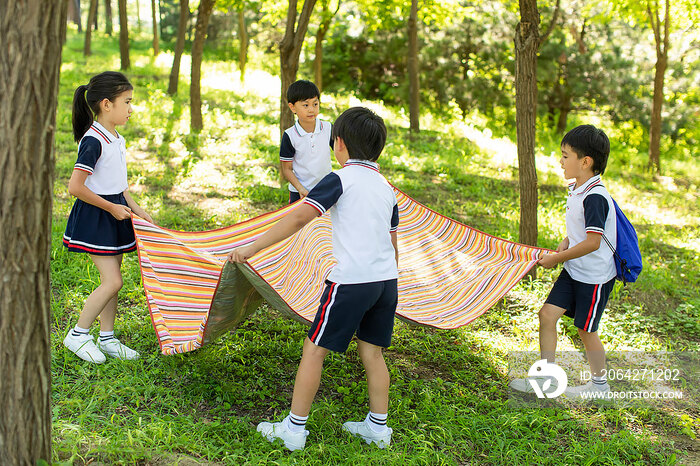 快乐的小学生铺野餐垫