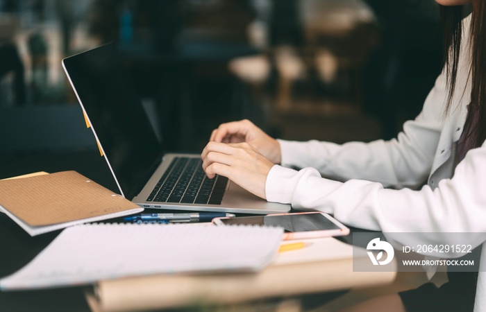 Young adult asian college student woman using laptop for study online course at cafe.