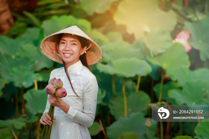A beautiful girl wearing a Vietnamese dress holds a large lotus flower for offering to the Buddha.