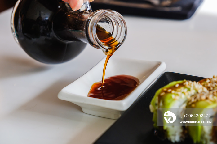 Bowl with tasty soy sauce. Sushi roll with eel and avocado. Traditional Japanese meal.