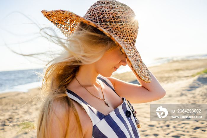 拉脱维亚里加沙滩上戴草帽的漂亮年轻女子侧视图