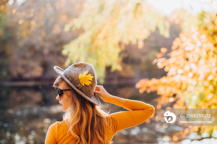 blonde in a yellow jacket on a background of autumn nature. the frame is lit by sunlight. A young wo