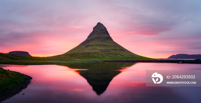 Picturesque panoramical landscape with Kirkjufell mountain, clear lake and cloudscape in sunset sky