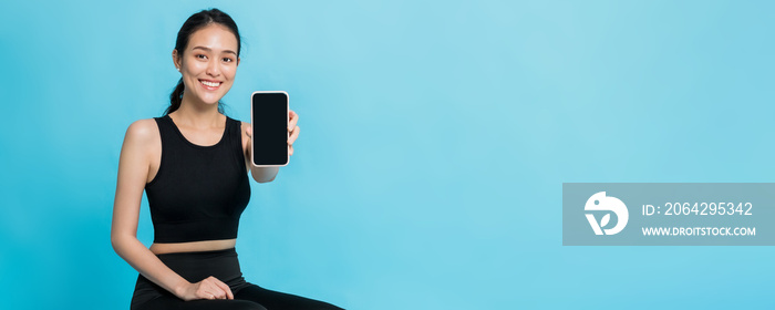 Asian beautiful happy woman holding smartphone after exercise isolated on blue colour background wit