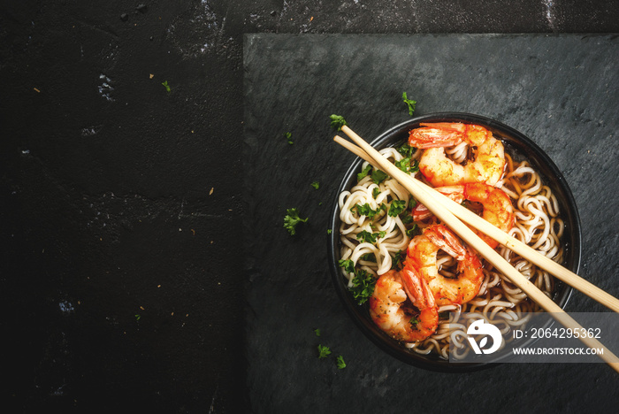 Asian soup with noodles (ramen), with miso paste, soy sauce, greens and shrimps prawn. On a black st