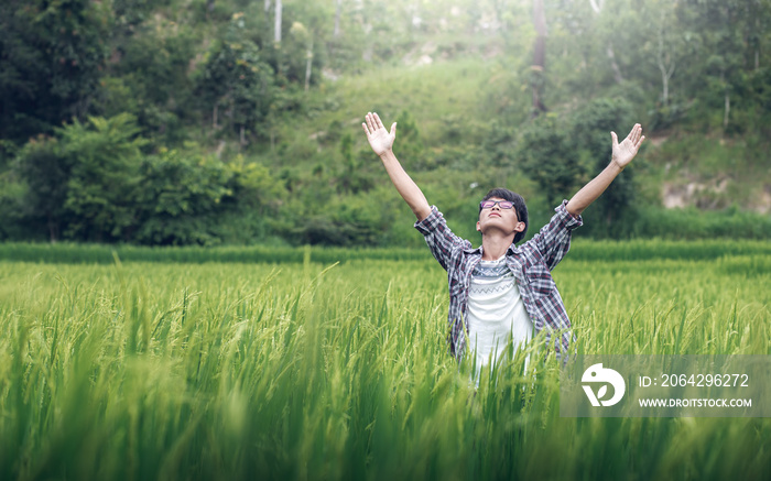 Young man raise up two hands for pray and worship to God in rice field, Christian concept.