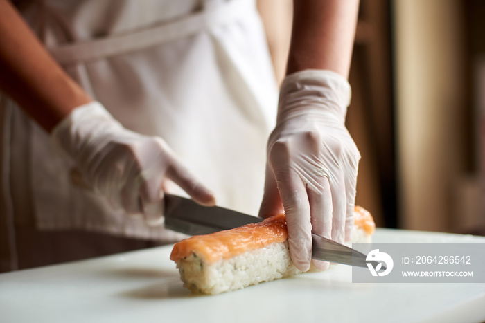 制作卷寿司的过程特写。厨师正在白板上切卷