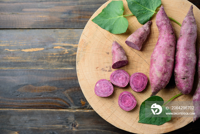 Raw purple sweet potatoes on wooden background