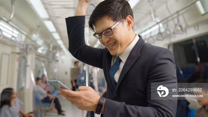 Businessman using mobile phone on public train . Urban city lifestyle commuting concept .