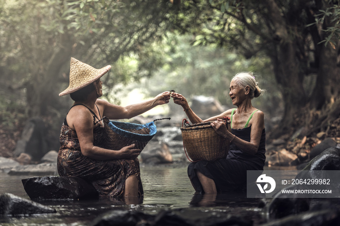 Old Asian woman working in cascade, Thailand