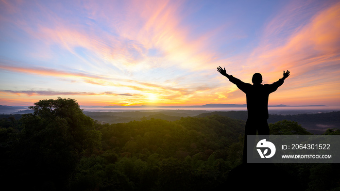 Silhouette of man raised hands with landscape mountains at sunset