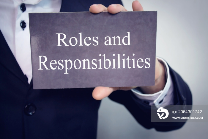 Roles and Responsibilities - Businessman holding chalkboard with text.