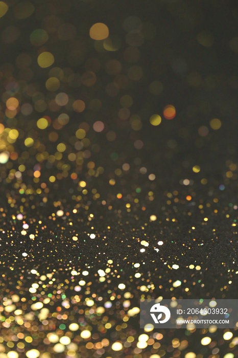 Golden bokeh background. Golden glitter on a black background.Festive New Year and Christmas shiny g