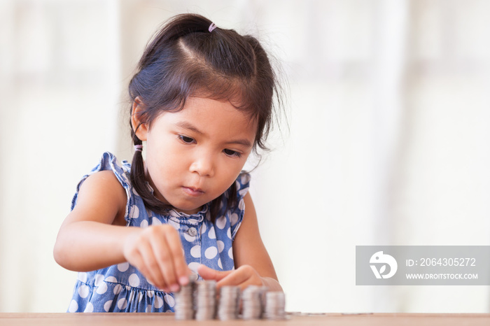 可爱的亚洲小女孩玩硬币赚大钱，孩子为未来的骗局存钱