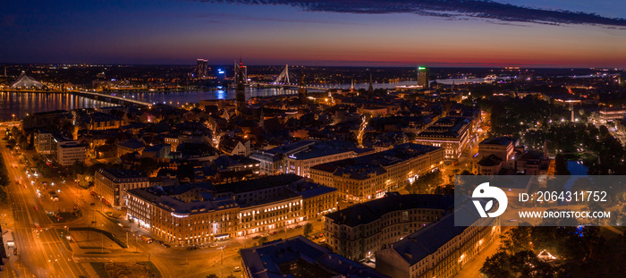 Panoramic view of the night city Riga at dusk with a St. Peters Church and river Daugava in the fore