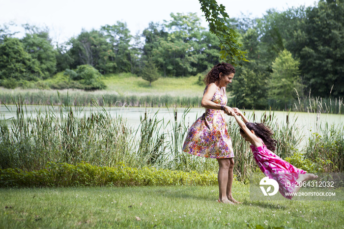 母亲和女儿在长满青草的湖岸玩耍