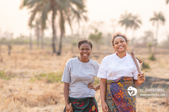 两位非洲女农民拿着农具微笑的画像