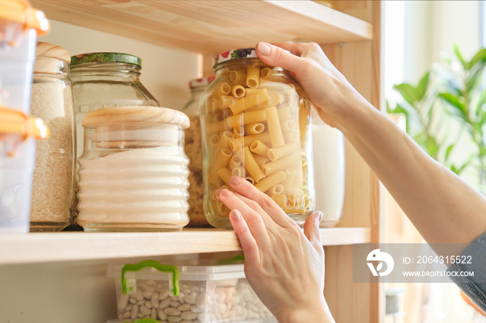 Food products in the kitchen. Woman taking jar of pasta