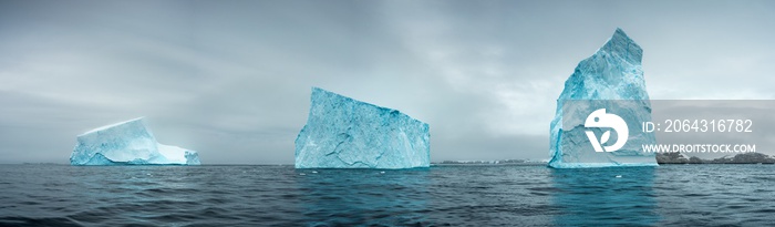 panorama with three giant icebergs in strait in Antarctica