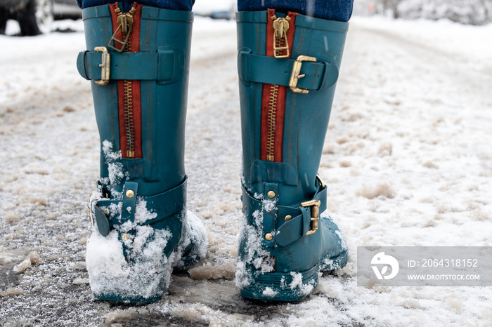 雪地湿滑的路。穿着橡胶靴的女人