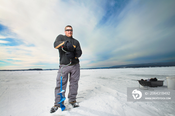 Man drilling hole in frozen lake