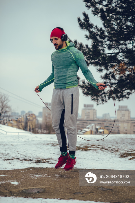 Muscular man jumping rope outside on a winter day