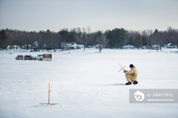 Ice fisherman on frozen lake