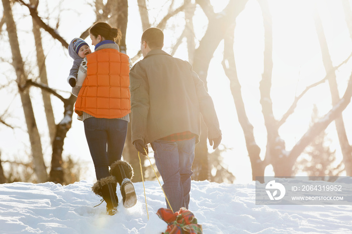 一对夫妇带着婴儿在雪地里行走的后视图