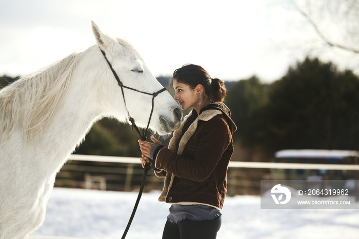 一个女人牵着马站在雪地里