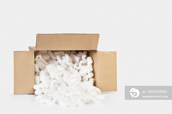 Caja de cartón llena de chips de espuma de poliestireno sobre un fondo gris claro. Vista de frente y