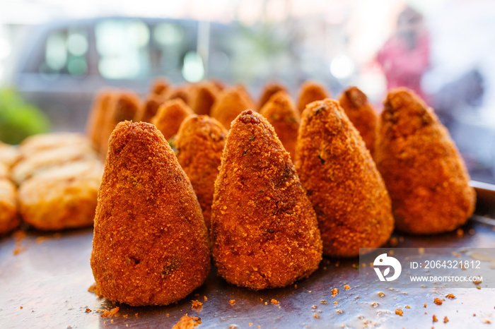 Arancini di riso fritti con pomodoro e carne in esposizione in una vetrina di una pizzeria