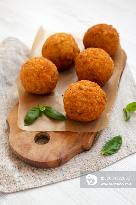 Homemade fried Arancini with basil on a rustic wooden board, low angle view. Italian rice balls. Clo