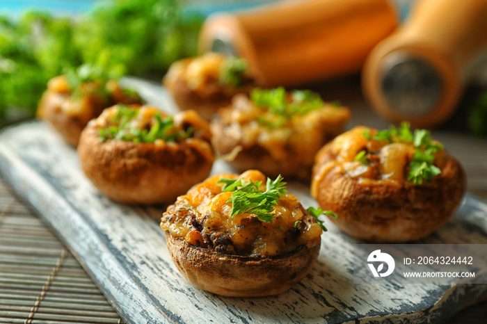 Stuffed mushrooms on wooden board, on table background