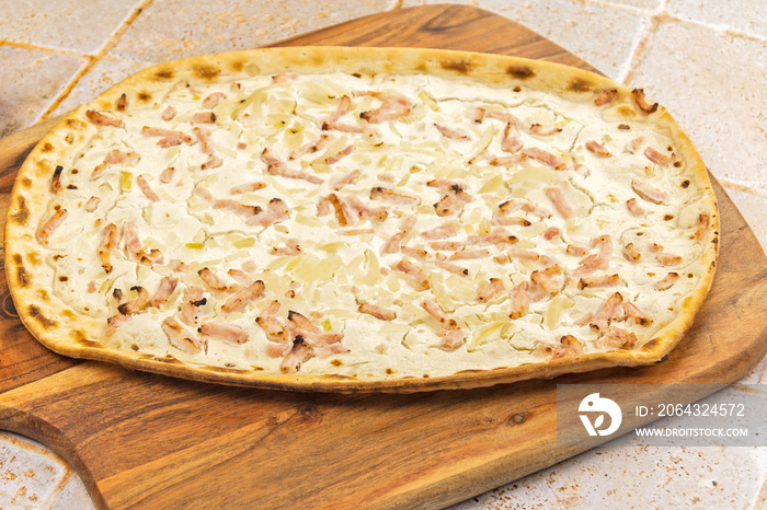 flammekueche (tarte flambée), spécialité alsacienne,  sur une planche à découper