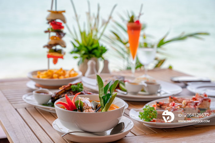 Variety of food, roasted pork ribs, beef steak, seafood and spicy soup on dining table