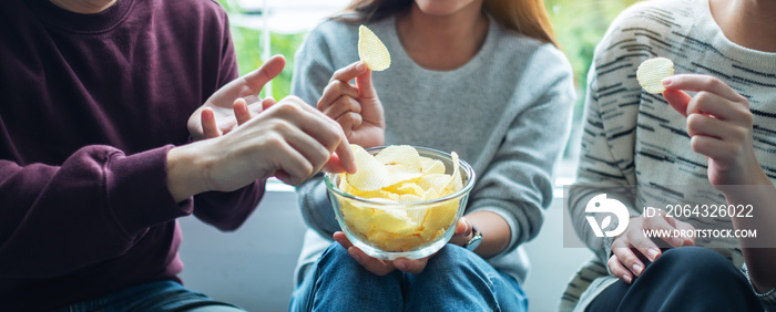 Closeup image of friends sharing and eating potato chips at home party together