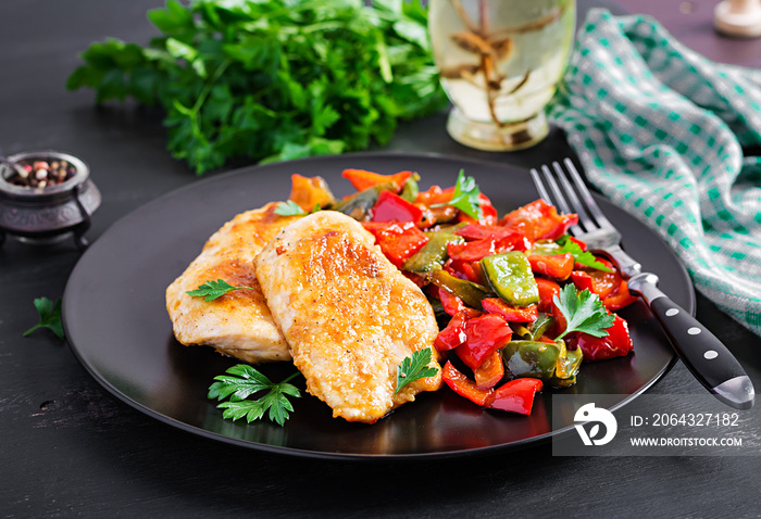 Grilled chicken fillets and sweet pepper on black plate.