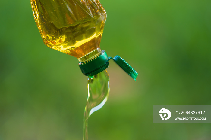 Vegetable oil pouring from bottle with nature background