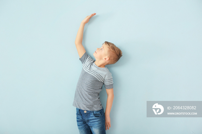 Cute little boy measuring height near color wall