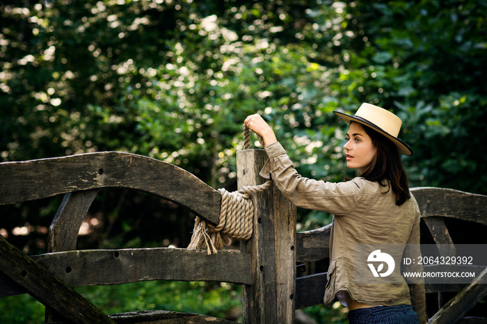 Young woman opening gate in forest