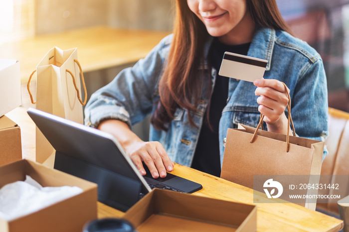一位年轻的亚洲女性使用平板电脑和信用卡通过邮政进行网上购物的特写图片