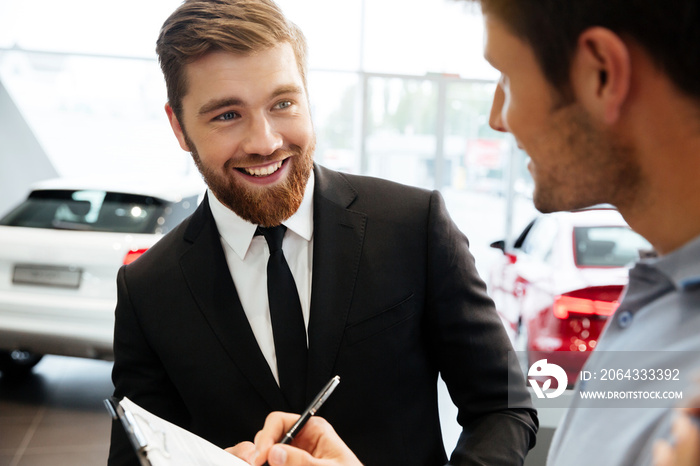 微笑的年轻经销商向男性客户销售新车